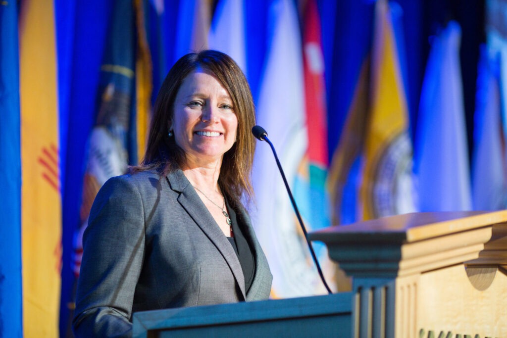 Photo of Brenda Burman standing at a podium to give a speech with US state flags in the background