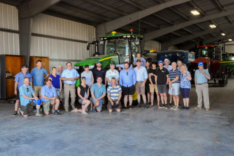 Group photo in warehouse in front of tractor